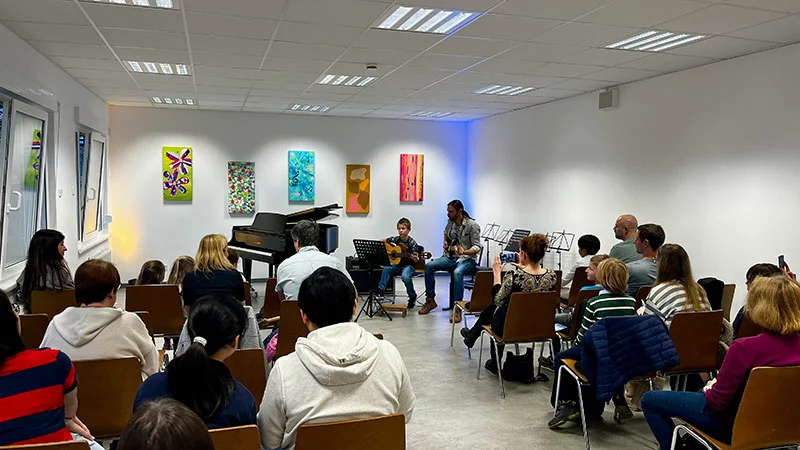 Kind spielt Gitarre mit Lehrer vor Publikum