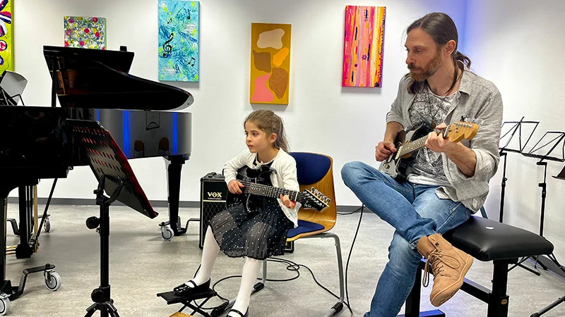 Mädchen spielt E-Gitarre mit Lehrer